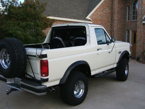 1991 Ford Bronco - 1991 Ford Bronco parked in front of a brick house, showing its rear and side profile.