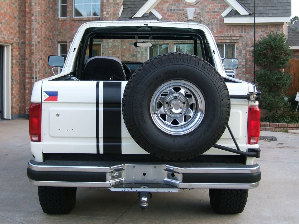 Rear of a white full-size Ford Bronco with tailgate spare and black stripe
