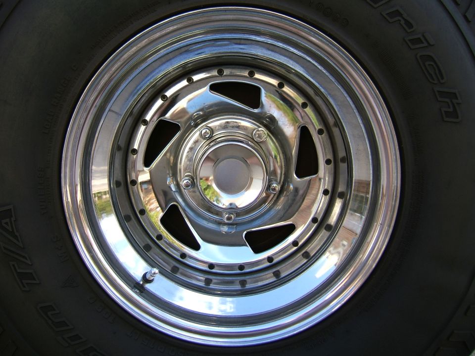 Chrome five-spoke wheel with a BFGoodrich tire. Supermotors.net logo in lower right