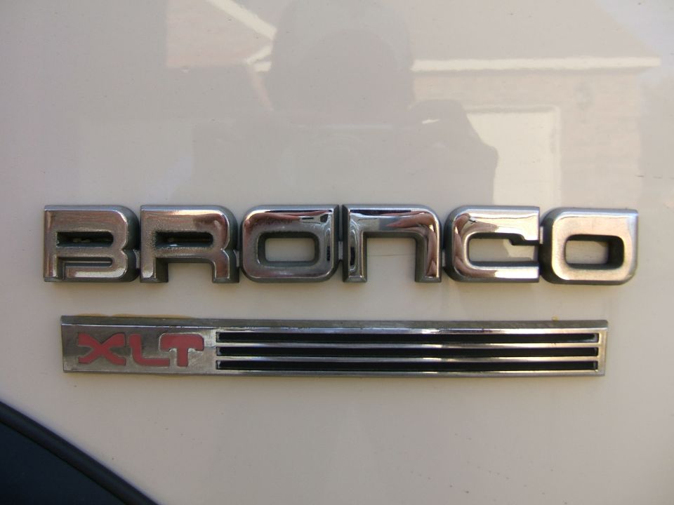 Chrome BRONCO fender lettering above red XLT badge on white body panel