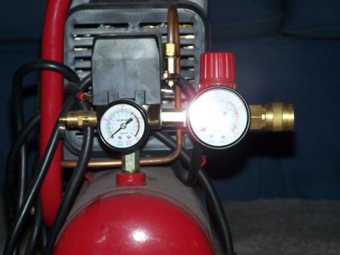 1995 Ford Bronco - Close-up view of the pressure gauges and regulator on a red air compressor.