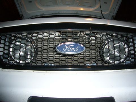 2000 Ford Crown Victoria - Front view of a white Ford Crown Victoria's grille, equipped with Hella fog lights and the iconic Ford emblem.