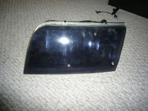 2000 Ford Crown Victoria - A single black headlight assembly is shown resting on a carpeted surface.