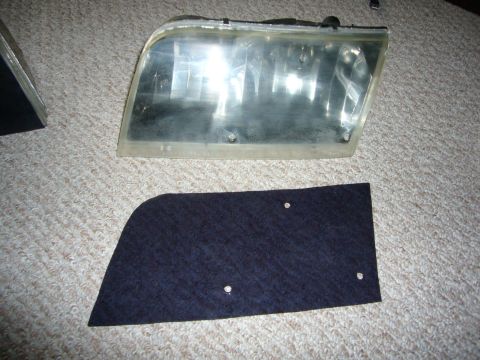 2000 Ford Crown Victoria - Headlight assembly and a separate trim piece shown on a carpeted surface.