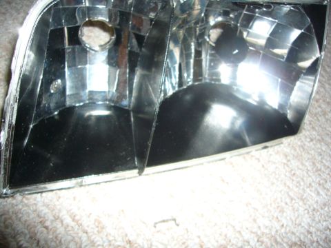 2000 Ford Crown Victoria - The interior of a car headlight assembly is shown, with reflective surfaces and bulb housings visible.