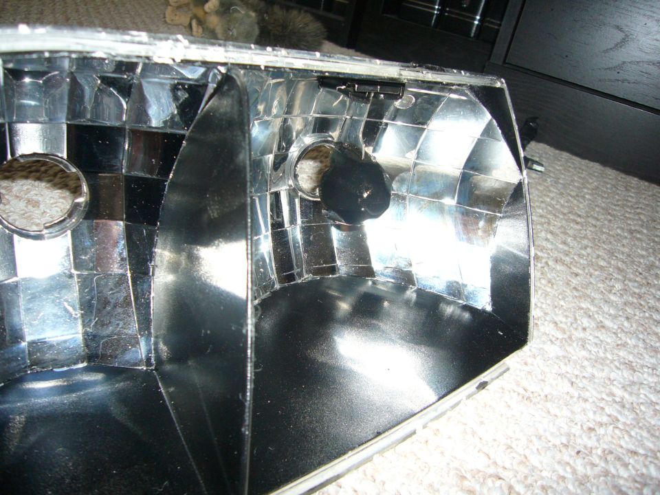 Headlight assembly interior with reflective facets and a black bulb socket