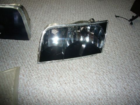 2000 Ford Crown Victoria - Pair of car headlights, likely for a Ford Crown Victoria, shown on a carpeted surface.