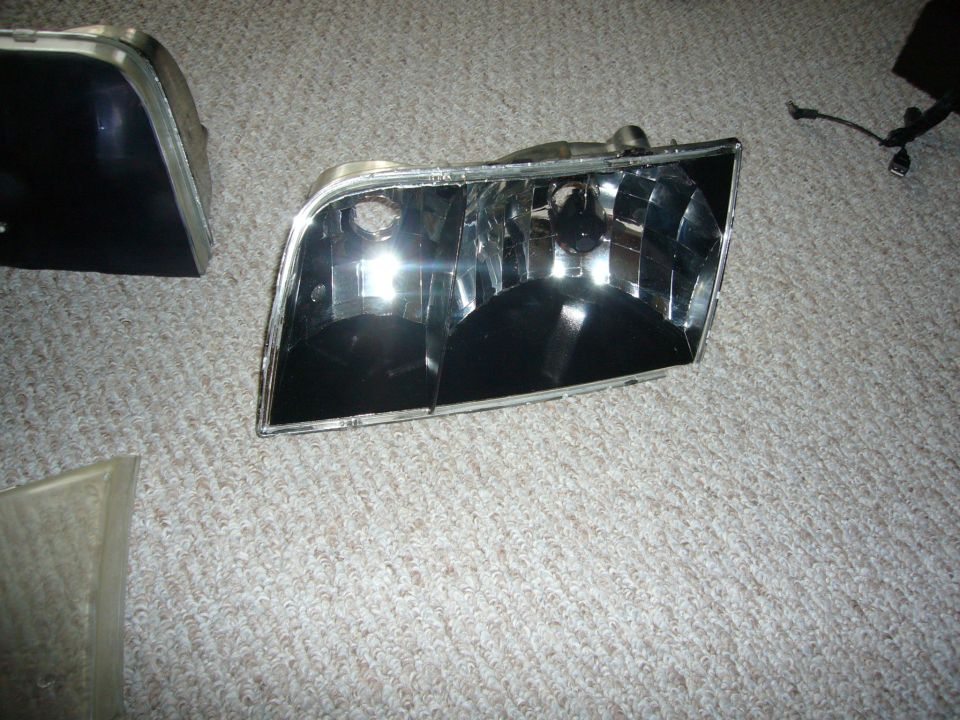 Two car headlights on a carpeted floor, one in focus