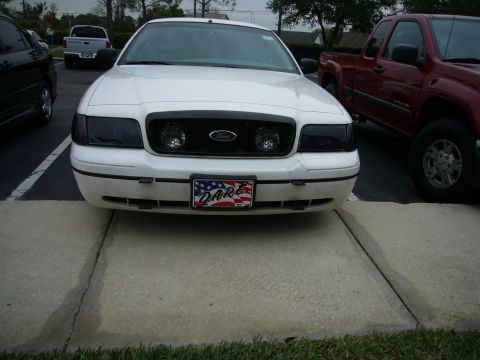 2000 Ford Crown Victoria - Front view of a white Ford Crown Victoria, blacked-out headlights and a D.A.R.E. license plate.