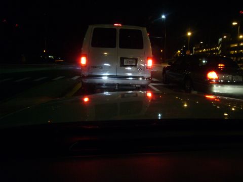 2000 Ford Crown Victoria - Two vehicles are seen from behind at night, one a white van and the other a dark sedan.