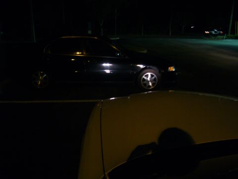 2000 Ford Crown Victoria - Two cars parked at night, one black sedan is visible in profile.