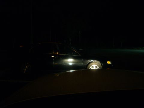 2000 Ford Crown Victoria - A black sedan is parked at night with its headlights illuminated.