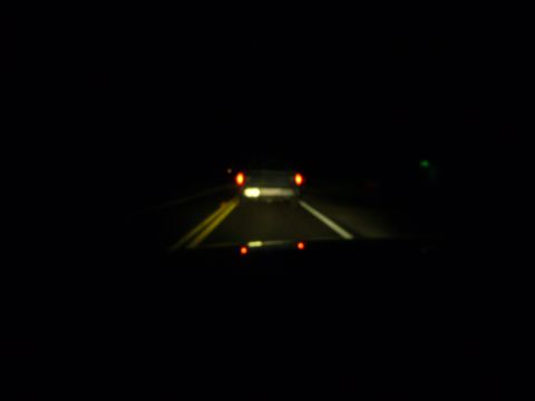 2000 Ford Crown Victoria - Driving at night, the taillights of the car ahead glow on the dark road.