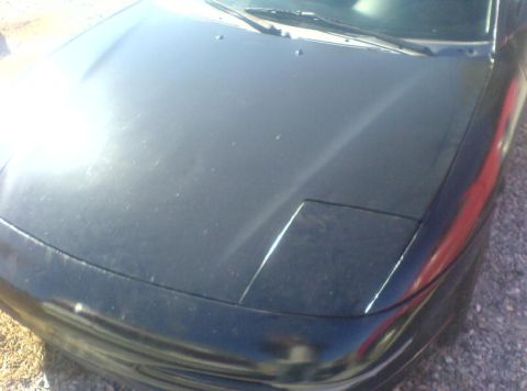1996 Ford Probe - The front of a black car shows a closed pop-up headlight and a portion of the hood.