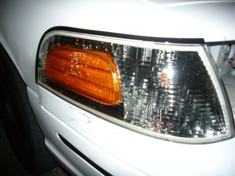 2000 Ford Crown Victoria - Close-up of a white car's front corner light assembly, showing the amber turn signal.