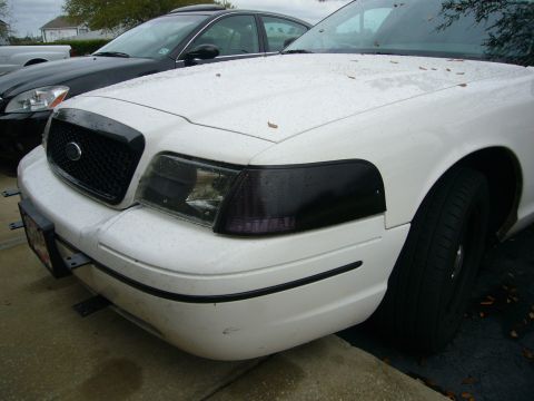 2000 Ford Crown Victoria - The front corner of a white 2000 Ford Crown Victoria is visible, parked next to another vehicle.