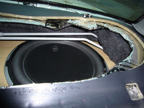 2000 Ford Crown Victoria - Rear deck audio install in progress with a large subwoofer mounted through a cut MDF baffle in the package tray. The carpet and torn foil-f…