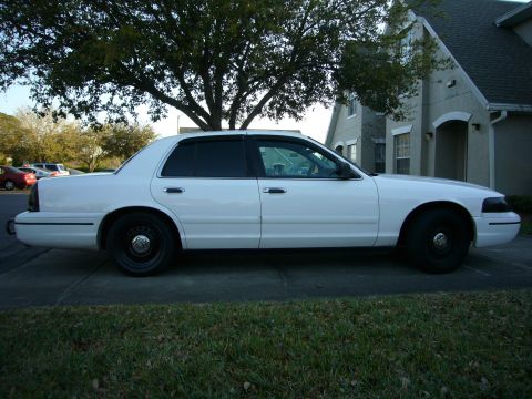 2000 Ford Crown Victoria - A white 2000 Ford Crown Victoria sedan is parked on a driveway in front of a house.