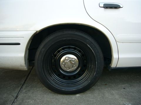2000 Ford Crown Victoria - Close-up of the rear wheel and door panel on a white Ford Crown Victoria.