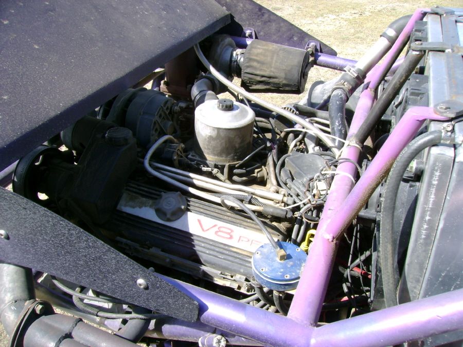 Engine bay with a V8 engine, purple roll cage, and air filter