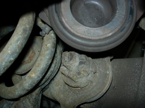1990 Ford Bronco - Close-up view of corroded vehicle suspension components, including a large nut and bolt.