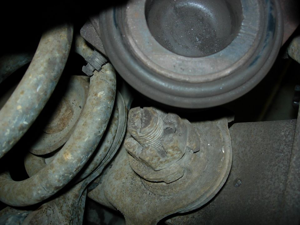 Close-up of rusty suspension parts with a large nut and bolt
