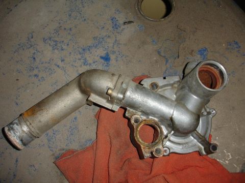 1992 Ford Taurus - A metal water pump, likely for a car, rests on a red cloth on a dusty surface.