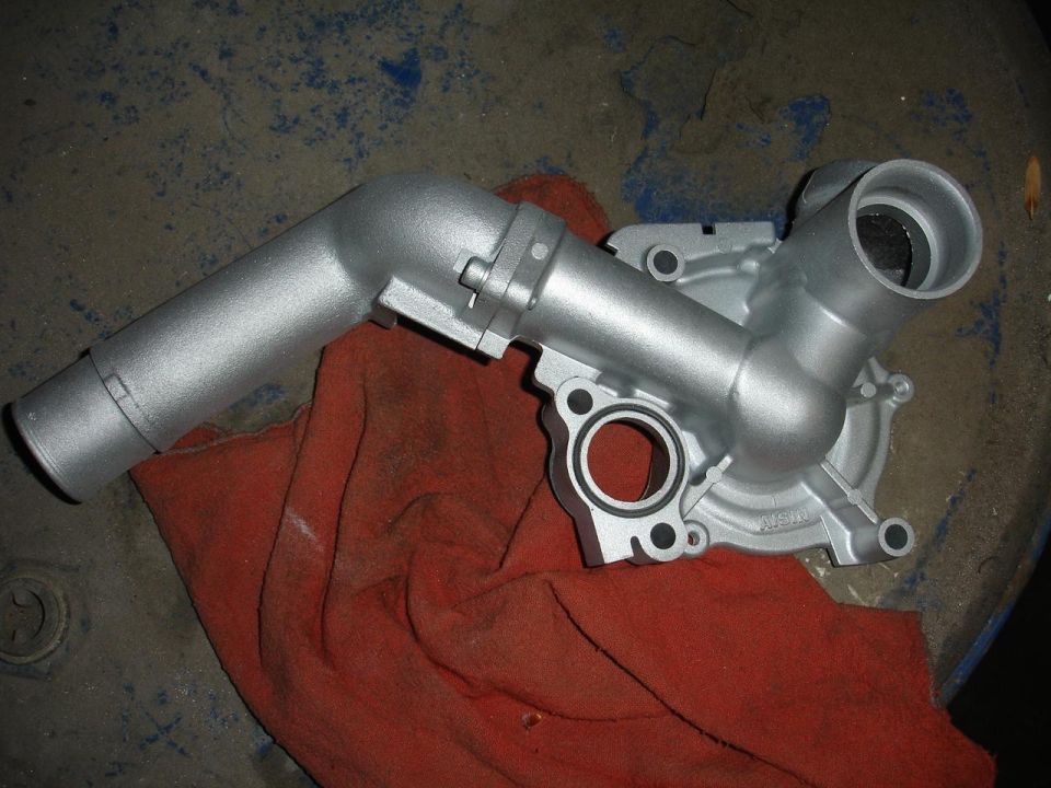 Freshly painted silver water pump and inlet housing on red rag
