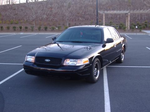 2001 Ford Crown Victoria - This black 2001 Ford Crown Victoria is parked in a lot, showing its front three-quarter view.