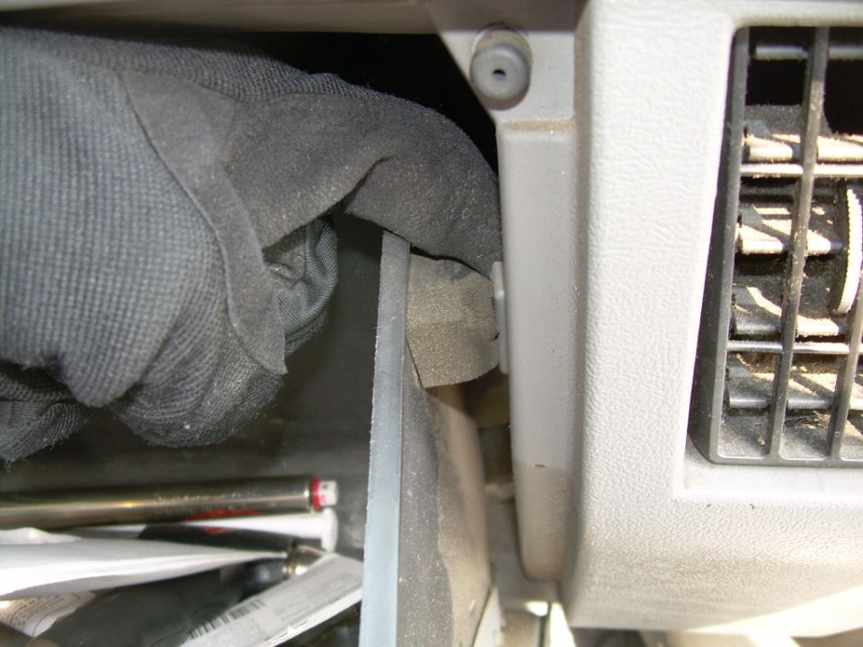 Open glove box being removed from a tan dashboard next to a plastic vent register