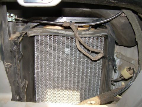 1988 Ford Bronco - Close-up view of a vehicle's heater core assembly, showing the metallic fins and surrounding ductwork.