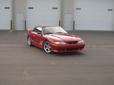 2007 Saleen S-302 - Red convertible sports car with aftermarket wheels and body kit parked outdoors.