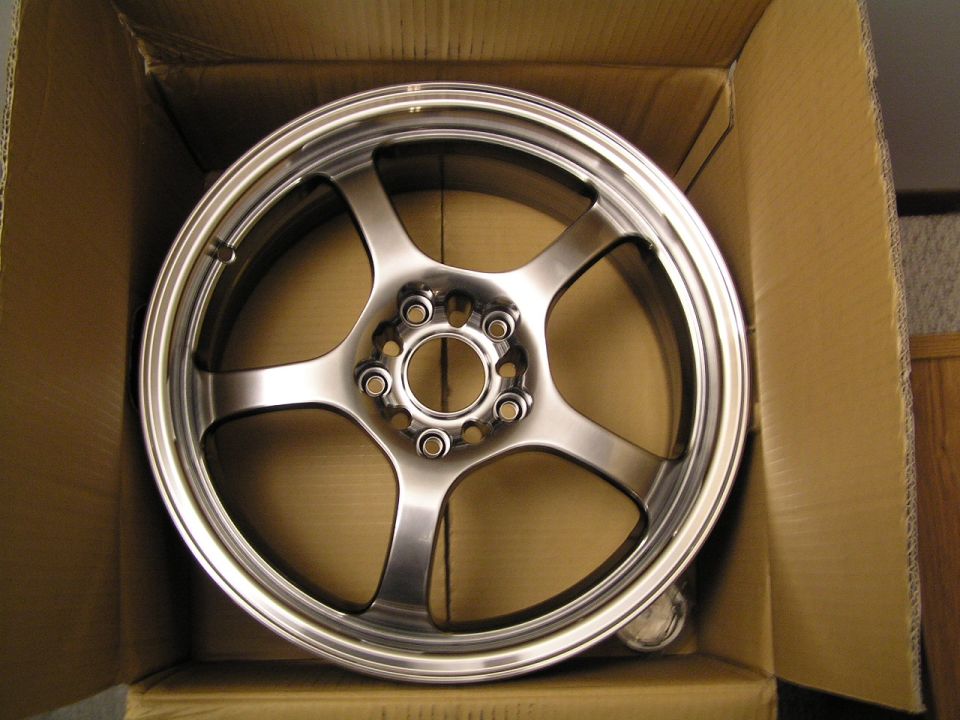 New polished six-spoke aluminum wheel in a cardboard box viewed from above