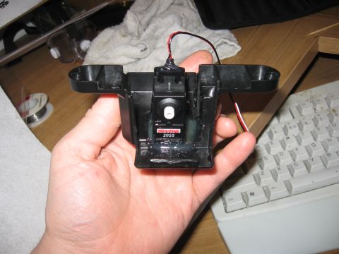 1990 Ford Bronco - A Traxxas 2055 servo motor part is held in a hand, with a keyboard visible in the background.