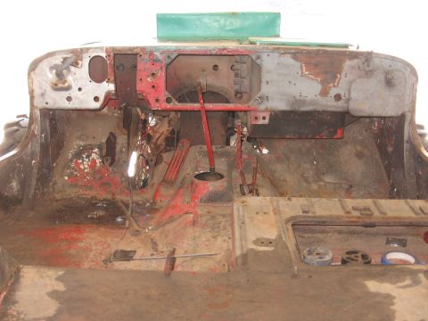 1986 Ford Bronco - The interior of a vehicle shows significant rust and exposed metal, with a green panel visible at the top.