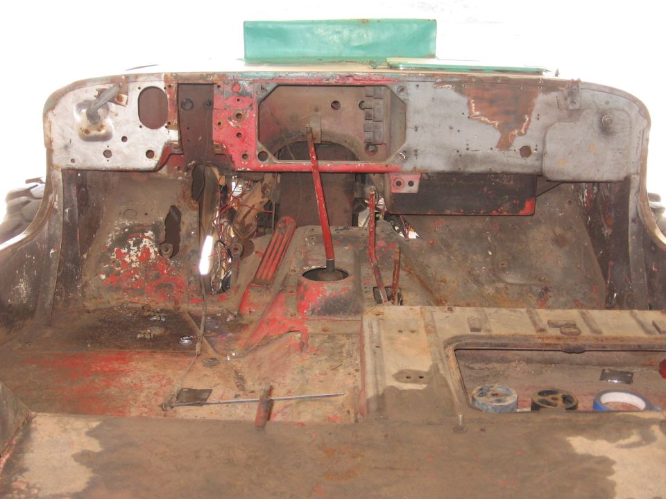 Interior of a rusty vehicle with exposed metal and red paint