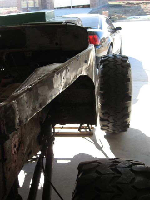 1986 Ford Bronco - Vehicle frame and tire in a garage setting, with another car in the background.