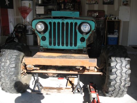 1986 Ford Bronco - This vintage Jeep CJ-5 is undergoing work in a garage, supported by jack stands.