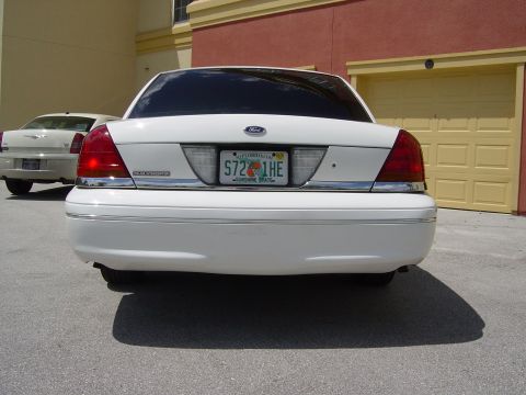 2000 Ford Crown Victoria - A white Ford Crown Victoria is parked in front of a garage, with another vehicle visible behind it.