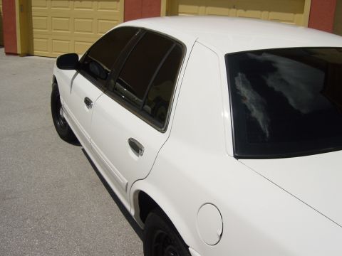 2000 Ford Crown Victoria - Side view of a white 2000 Ford Crown Victoria sedan parked in front of a yellow garage door.