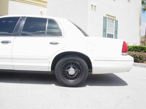 2000 Ford Crown Victoria - A white 2000 Ford Crown Victoria is seen from the side, parked in front of a building.
