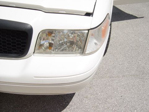 2000 Ford Crown Victoria - Front corner view of a white 2000 Ford Crown Victoria, showing the headlight and grille detail.