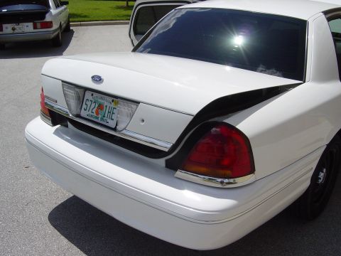 2000 Ford Crown Victoria - The rear of a white Ford Crown Victoria is shown with its trunk ajar, revealing the interior.
