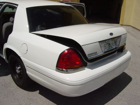 2000 Ford Crown Victoria - Rear view of a white 2000 Ford Crown Victoria with its trunk open, showing black steel wheels and chrome accents.