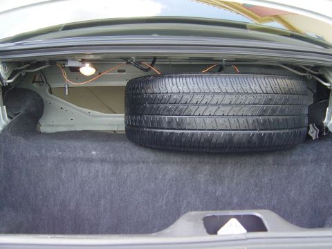 2000 Ford Crown Victoria - The trunk of a car contains a spare tire and a light fixture.