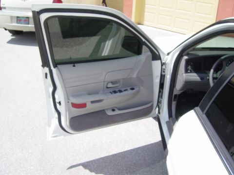 2000 Ford Crown Victoria - Interior view of a white sedan showing the driver's side door panel and dashboard.