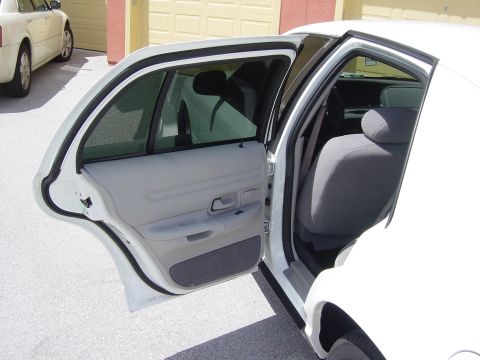 2000 Ford Crown Victoria - View of the interior of a white sedan with rear doors open, parked next to another vehicle.