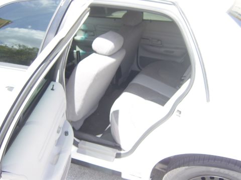 2000 Ford Crown Victoria - Interior view of a white 2000 Ford Crown Victoria, highlighting the cloth seating and open driver's door.