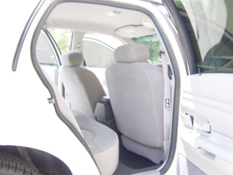 2000 Ford Crown Victoria - The interior of a white sedan shows the rear seats and door panel with the door open.