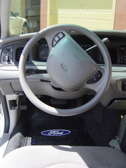 2000 Ford Crown Victoria - The interior of a 2000 Ford Crown Victoria is shown, the steering wheel and a Ford-branded floor mat.